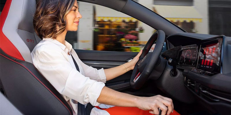 Driver in a Volkswagen GTI interior using the steering wheel and gear selector.