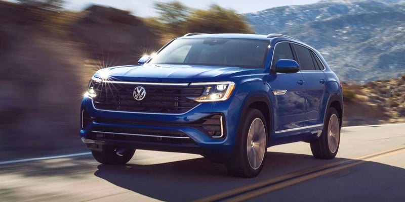 Blue 2026 Volkswagen Atlas front three-quarter view driving in daylight.