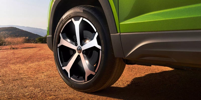 Close-up of a Volkswagen wheel rim on a green SUV.