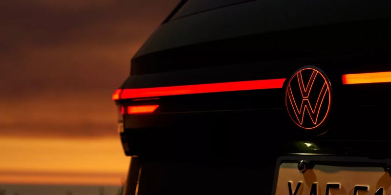 Rear view of a Volkswagen vehicle with illuminated taillight and VW emblem.